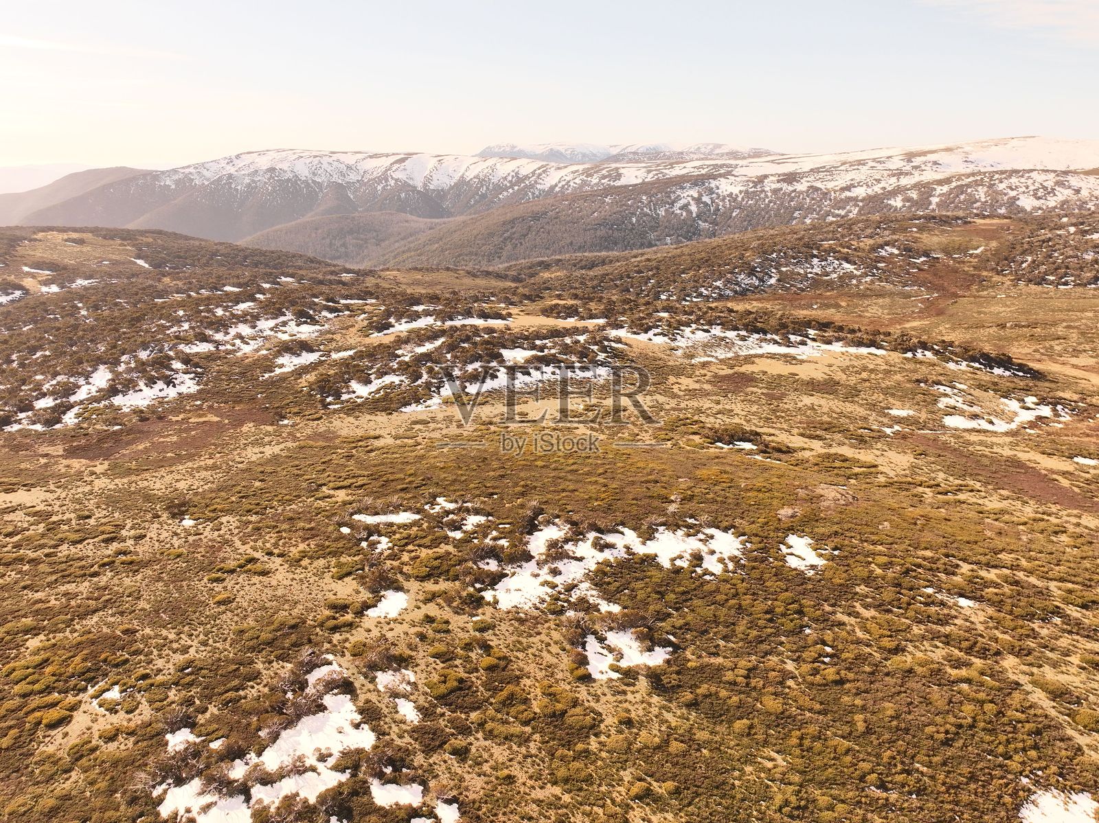 广阔起伏的景观,点缀着雪地和棕色植被照片摄影图片