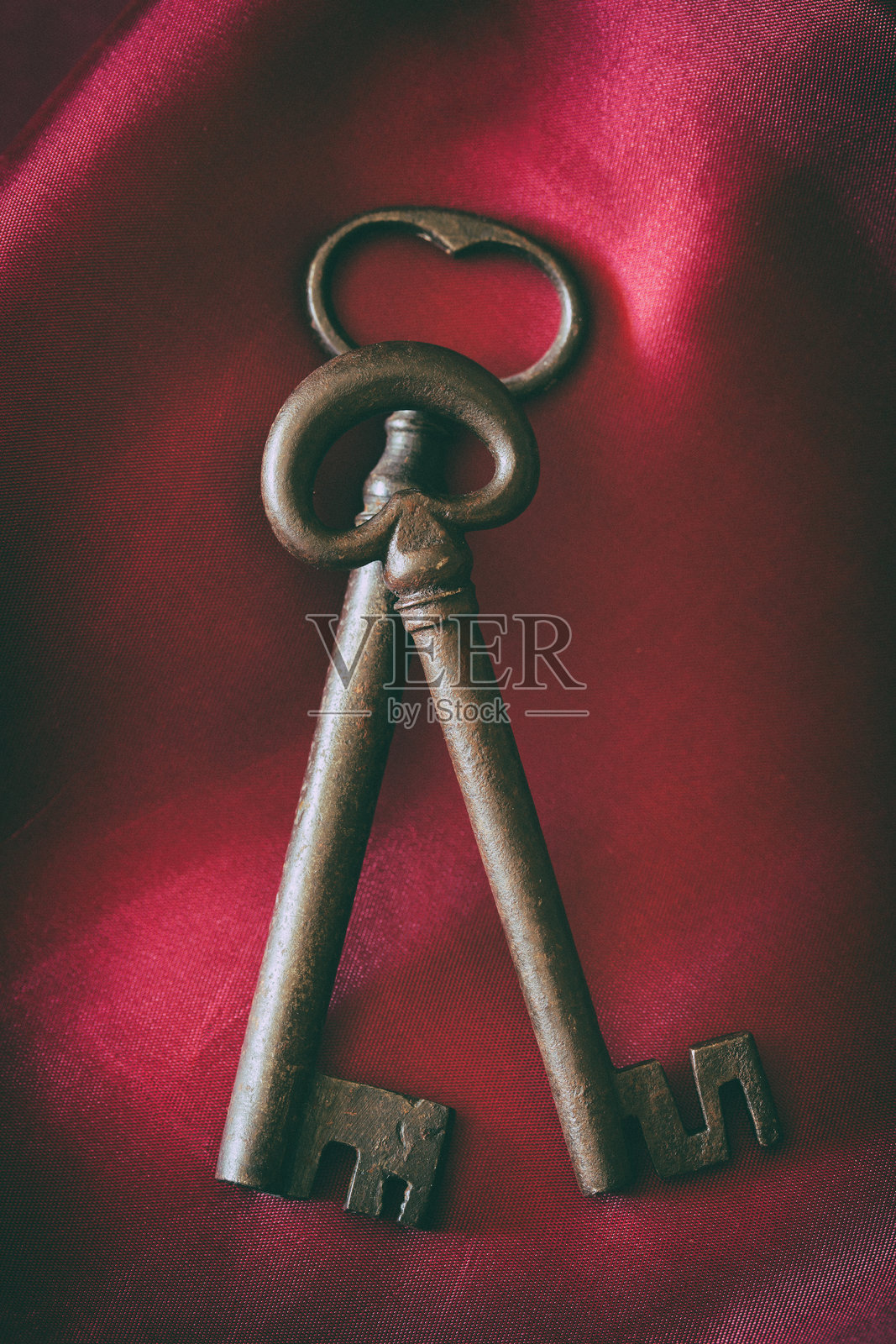 两把华丽的古董钥匙静静地放在红色天鹅绒布料上照片摄影图片