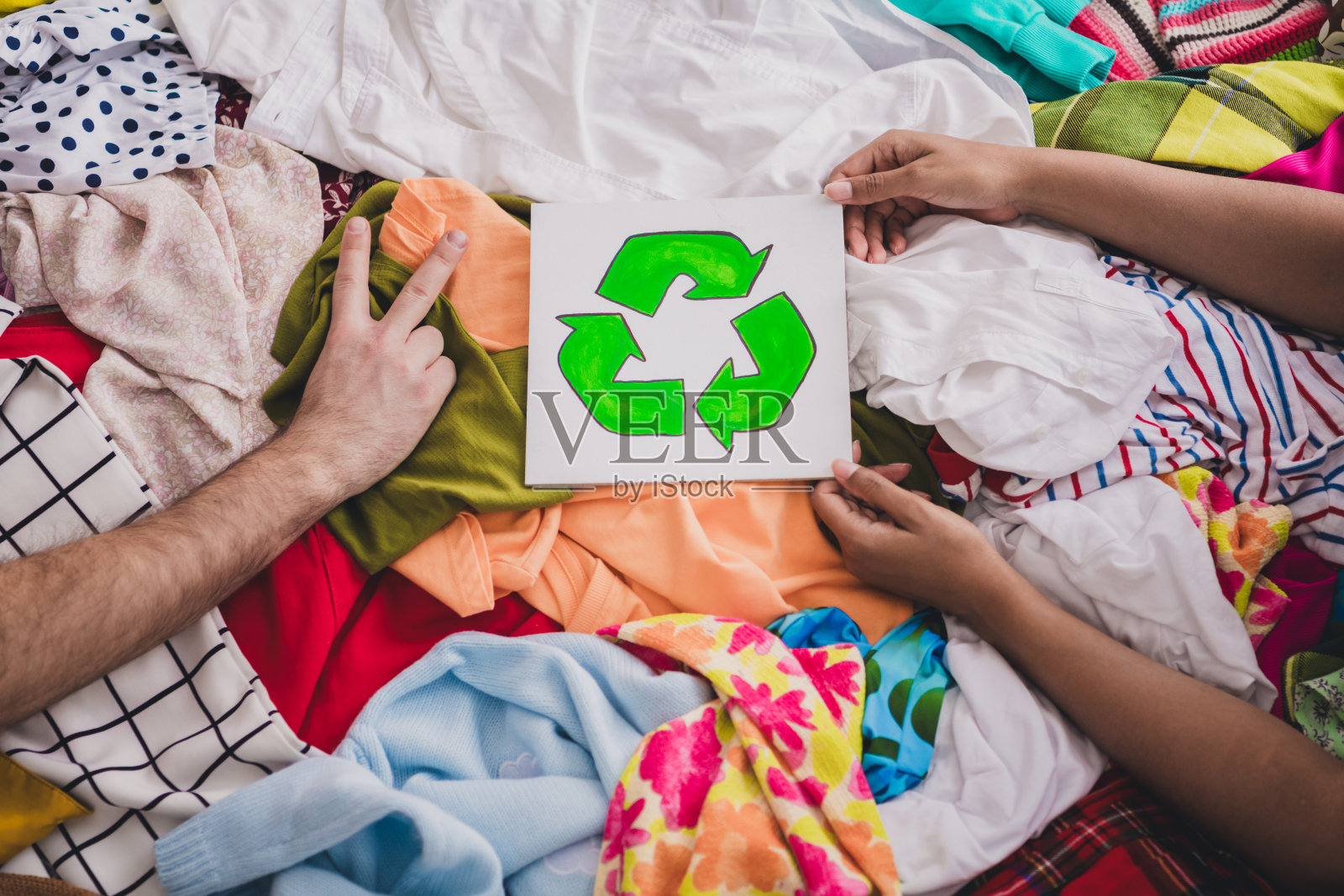 年轻女性在客厅里与捐赠衣物和回收标志,宣传环保意识和可持续时尚照片摄影图片