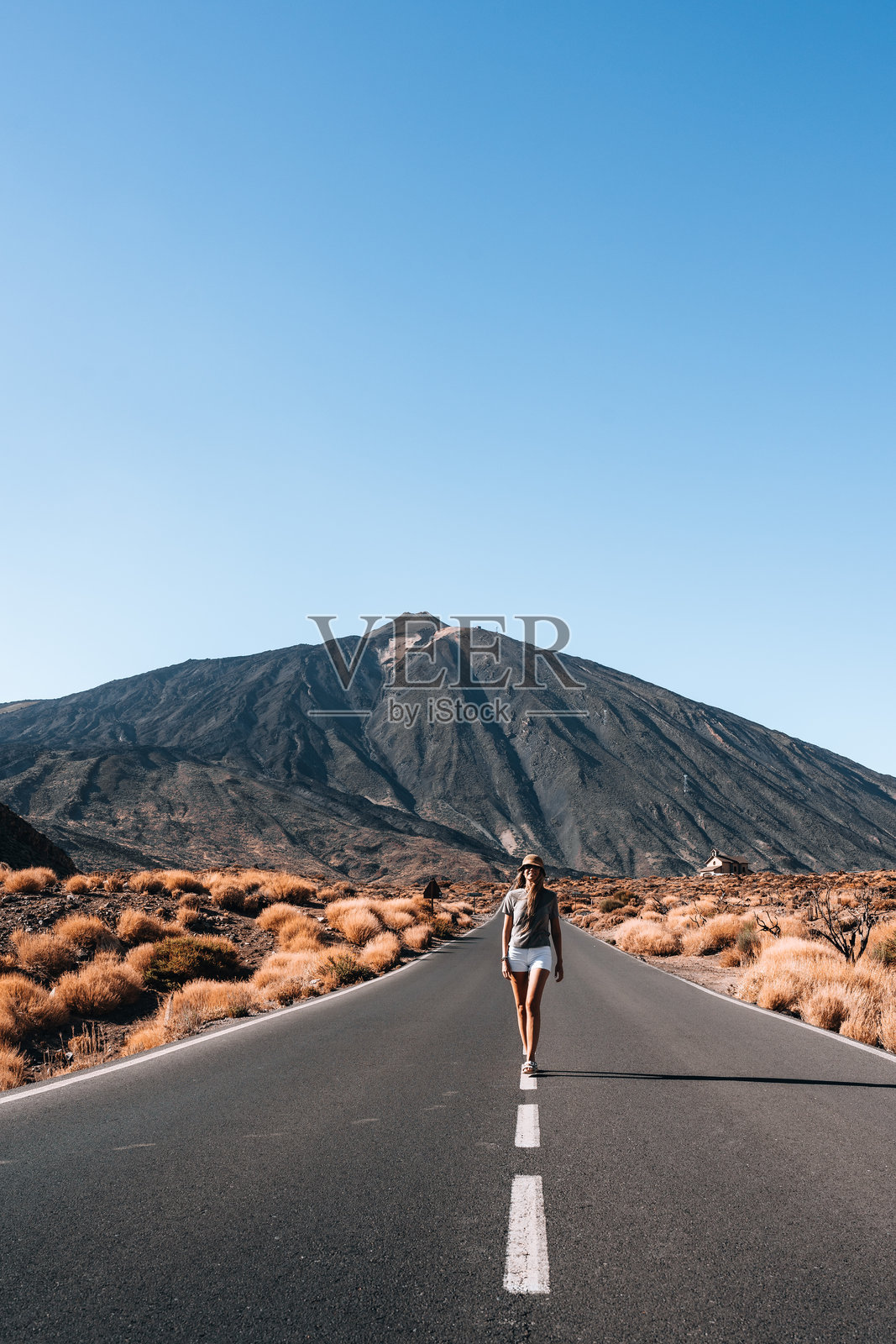一位女性在特内里费的泰德山前沿着道路行走照片摄影图片