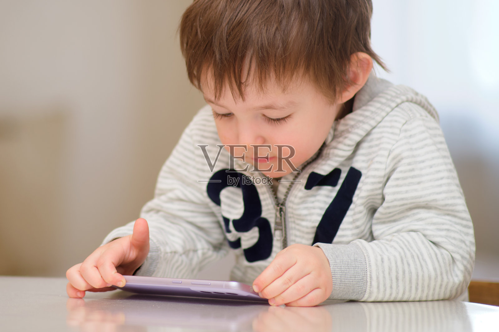 快乐的宝宝正在玩手机。一个微笑的孩子在看手机。两岁的小孩。照片摄影图片