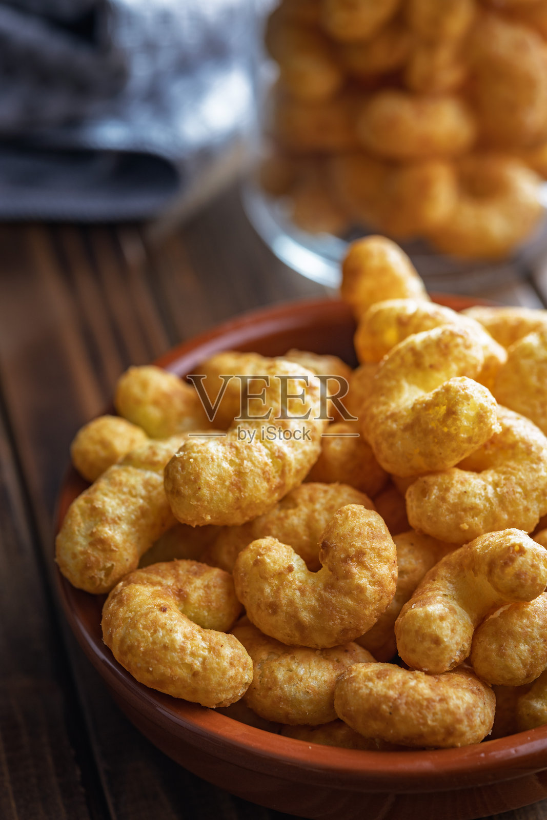 木桌上碗里的脆皮花生翻转零食。照片摄影图片