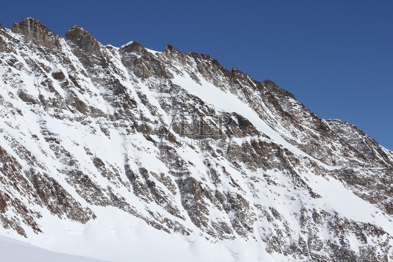 伯尔尼阿尔卑斯山脉中,蓝天映衬下的岩石和雪覆盖的山脊特写照片摄影图片