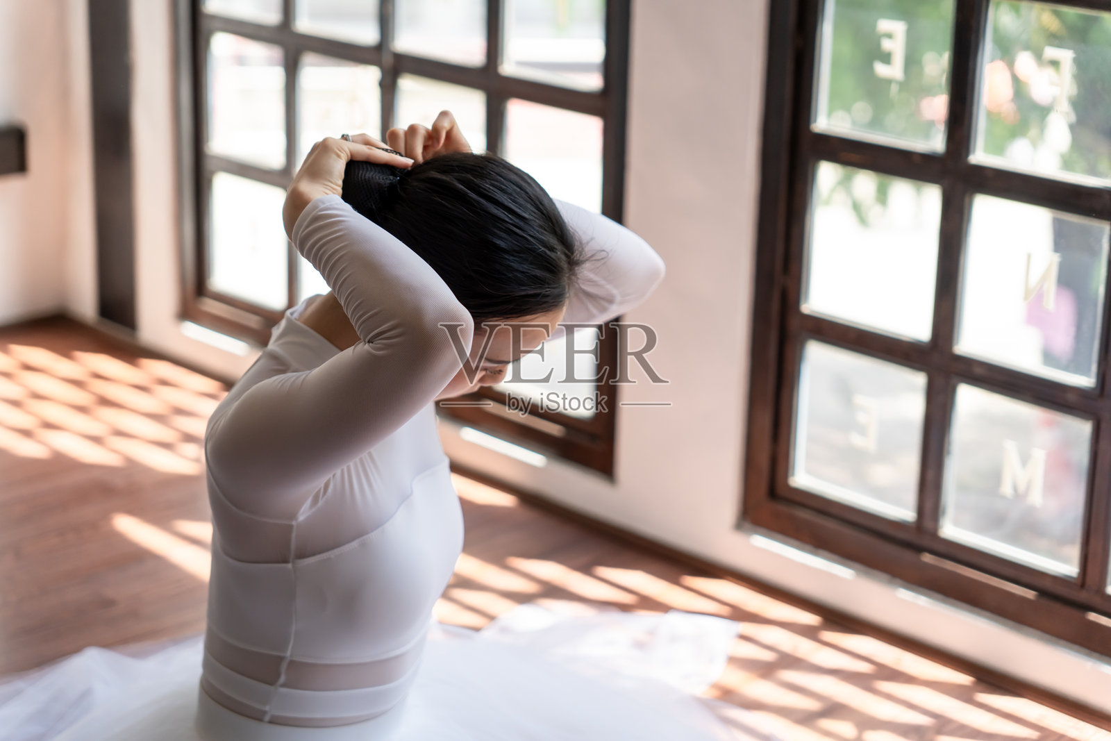 亚洲女孩芭蕾舞者在芭蕾课上准备将头发扎成发髻。芭蕾舞者正在整理她的头发。照片摄影图片