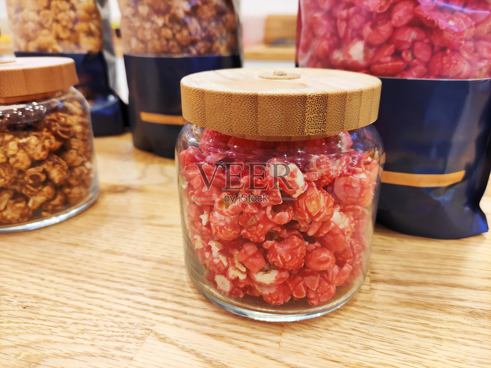 甜美的多彩松脆爆米花装在玻璃罐中,陈列在商店橱窗上照片摄影图片