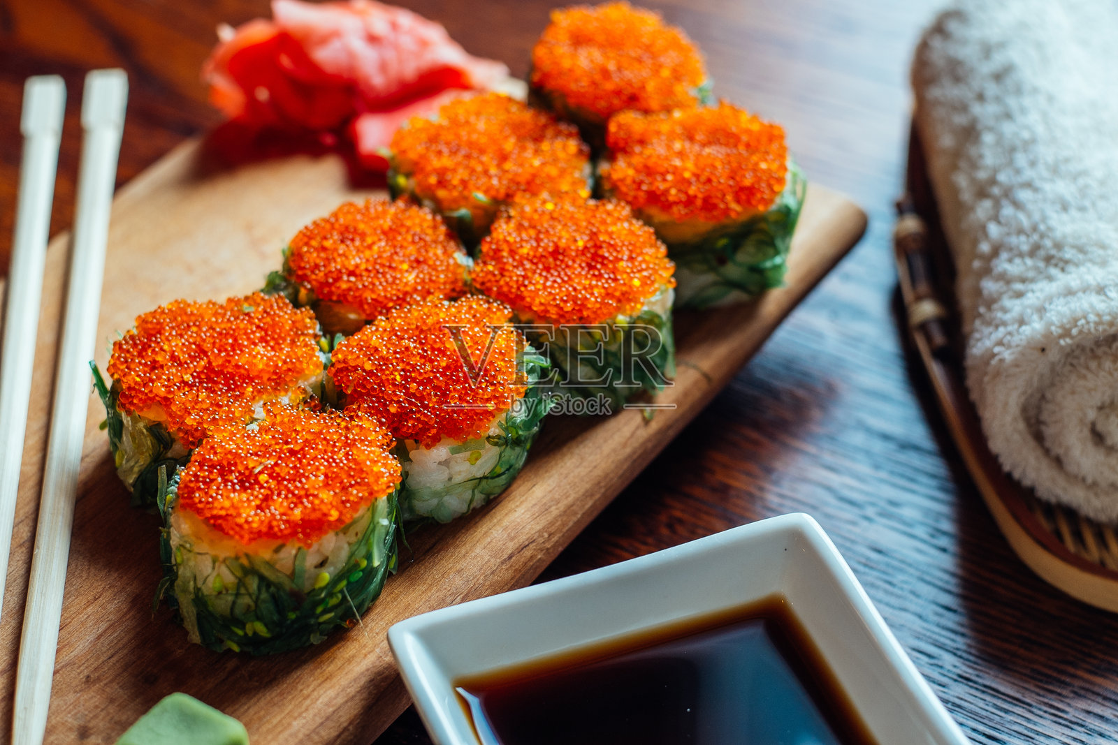 一盘寿司,配有酱汁和筷子,放在木桌上照片摄影图片