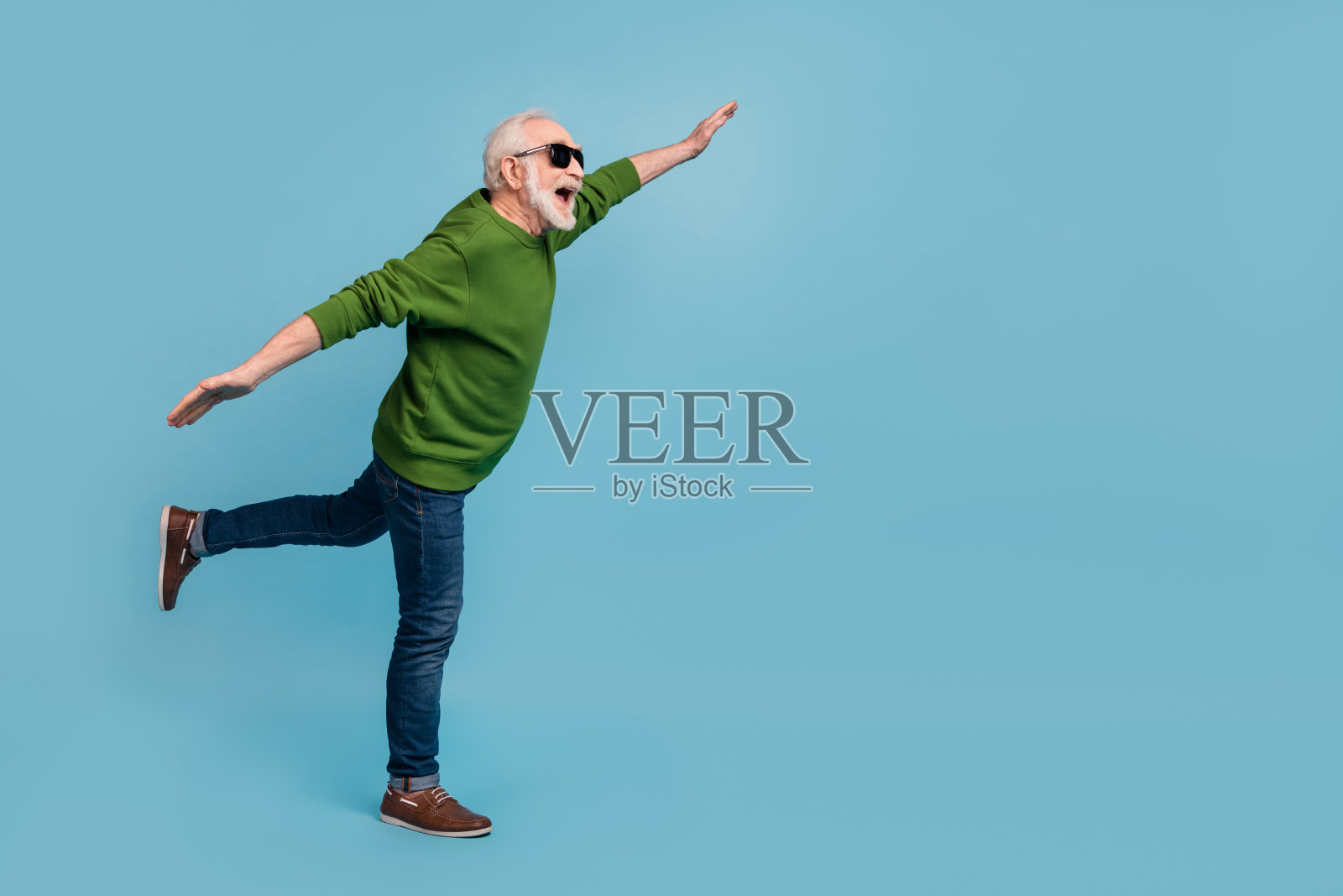 全身侧面照,开心兴奋的人双臂张开,空旷的空间,背景为蓝色。照片摄影图片