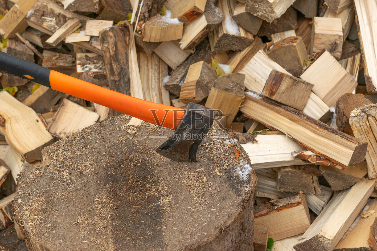 砍柴斧放在树桩上,背景是新切割的木柴照片摄影图片