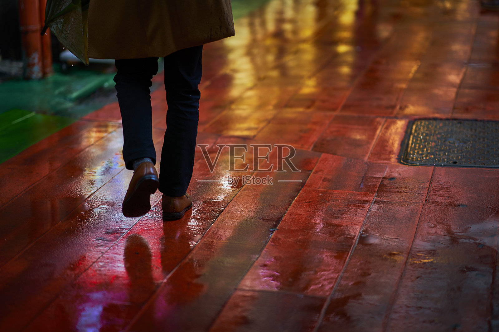 夜晚城市中,男子在湿滑人行道上行走的下半身照片摄影图片