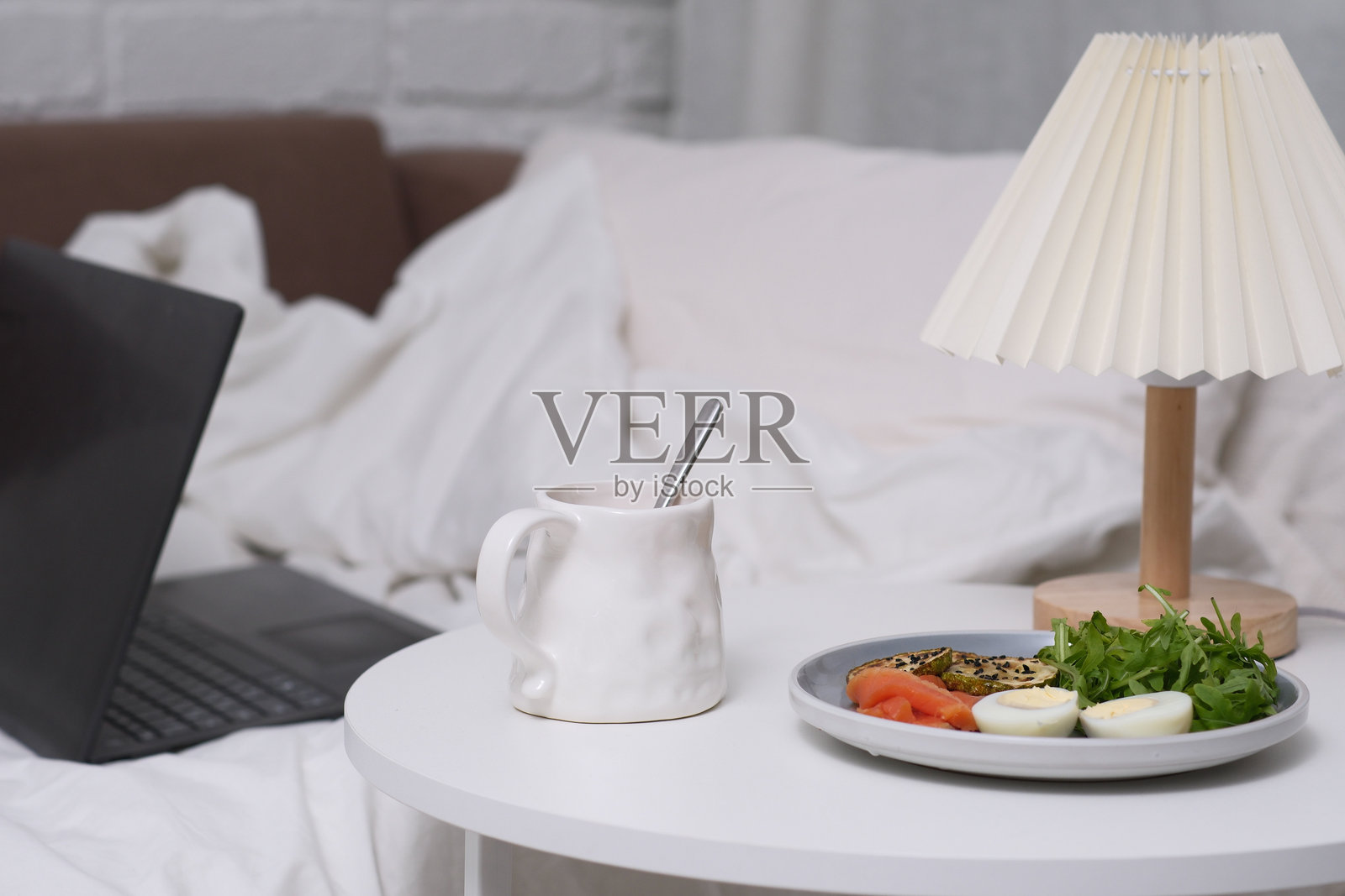 享受舒适的床上早餐,伴随笔记本电脑和温暖的灯光,带来舒适与放松。照片摄影图片