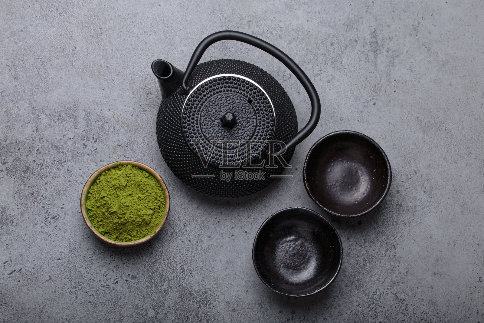 抹茶茶道套装,黑色铁壶和两个杯子置于灰色石材背景上,传统日本茶道俯视图照片摄影图片