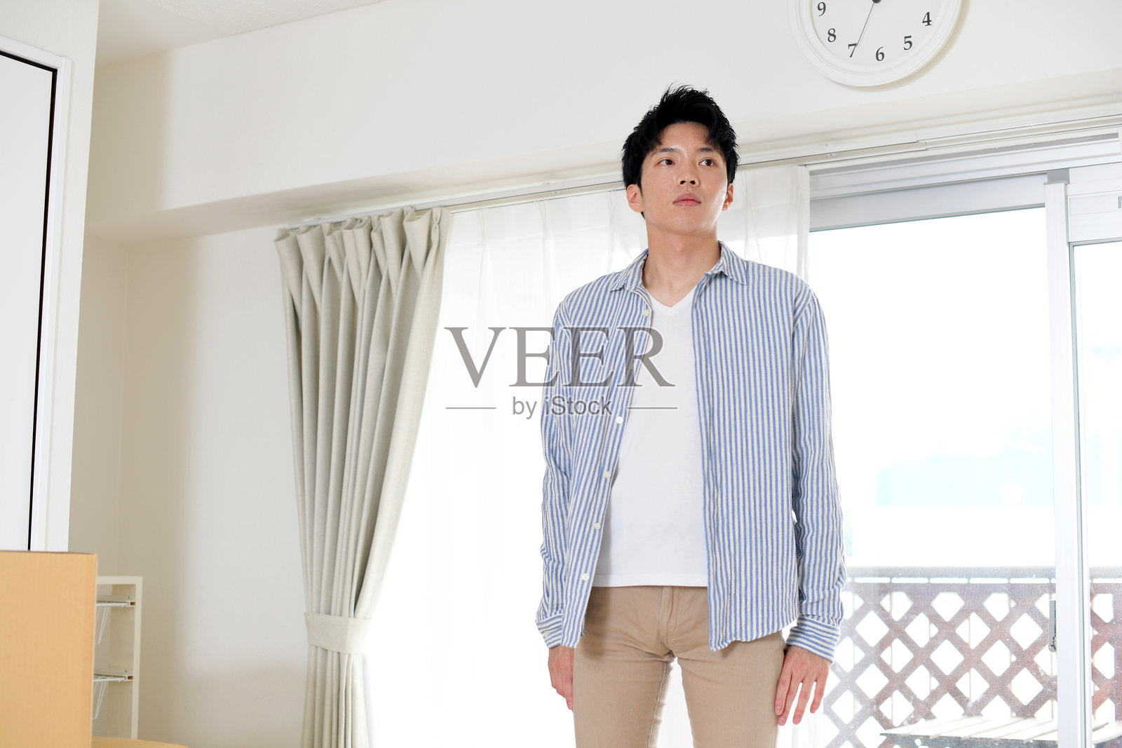 一位面带严肃表情的年轻亚洲男子站在房间里照片摄影图片