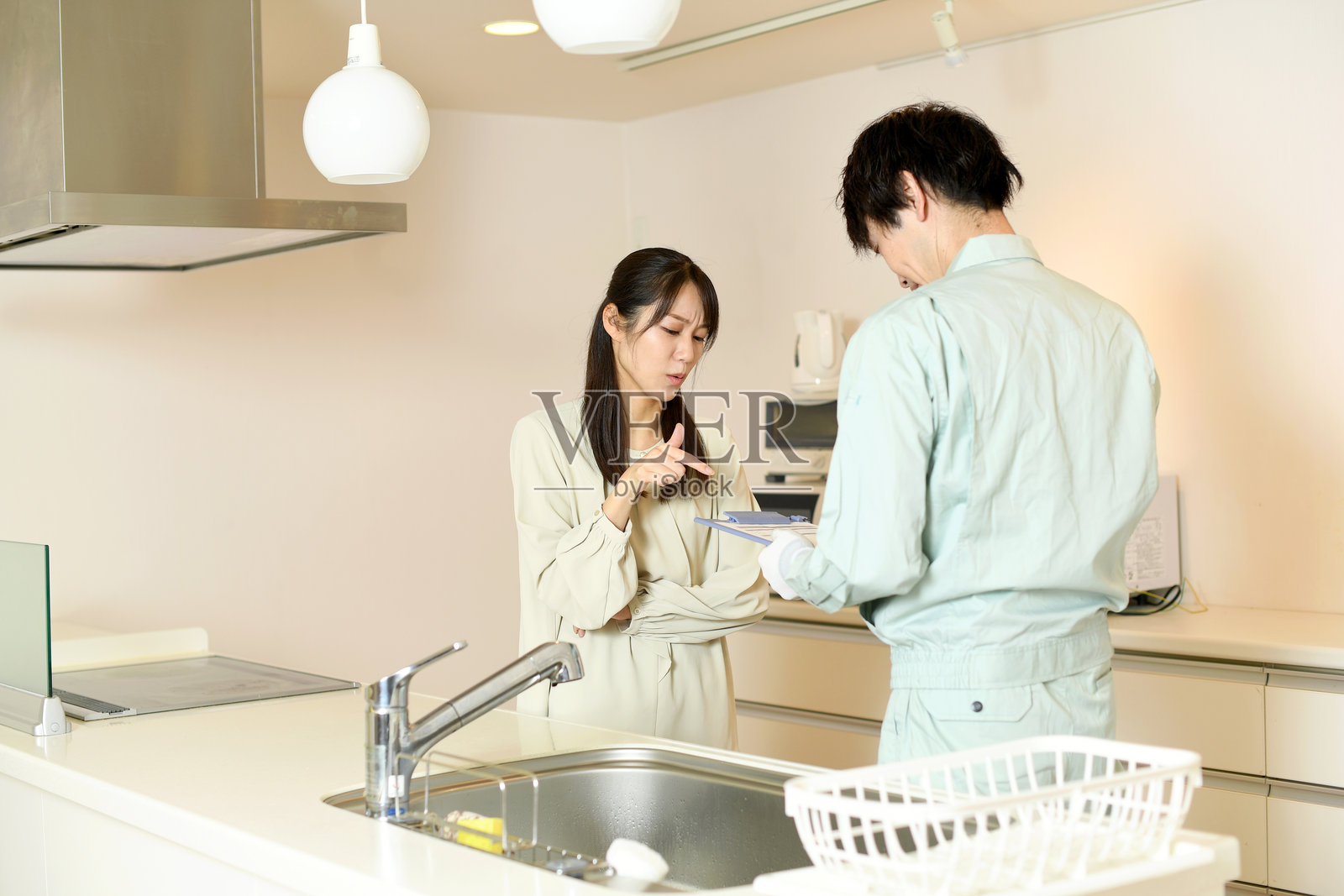 一位女性顾客和一位男性员工在住宅楼的系统厨房前抱怨并被大声斥责。照片摄影图片