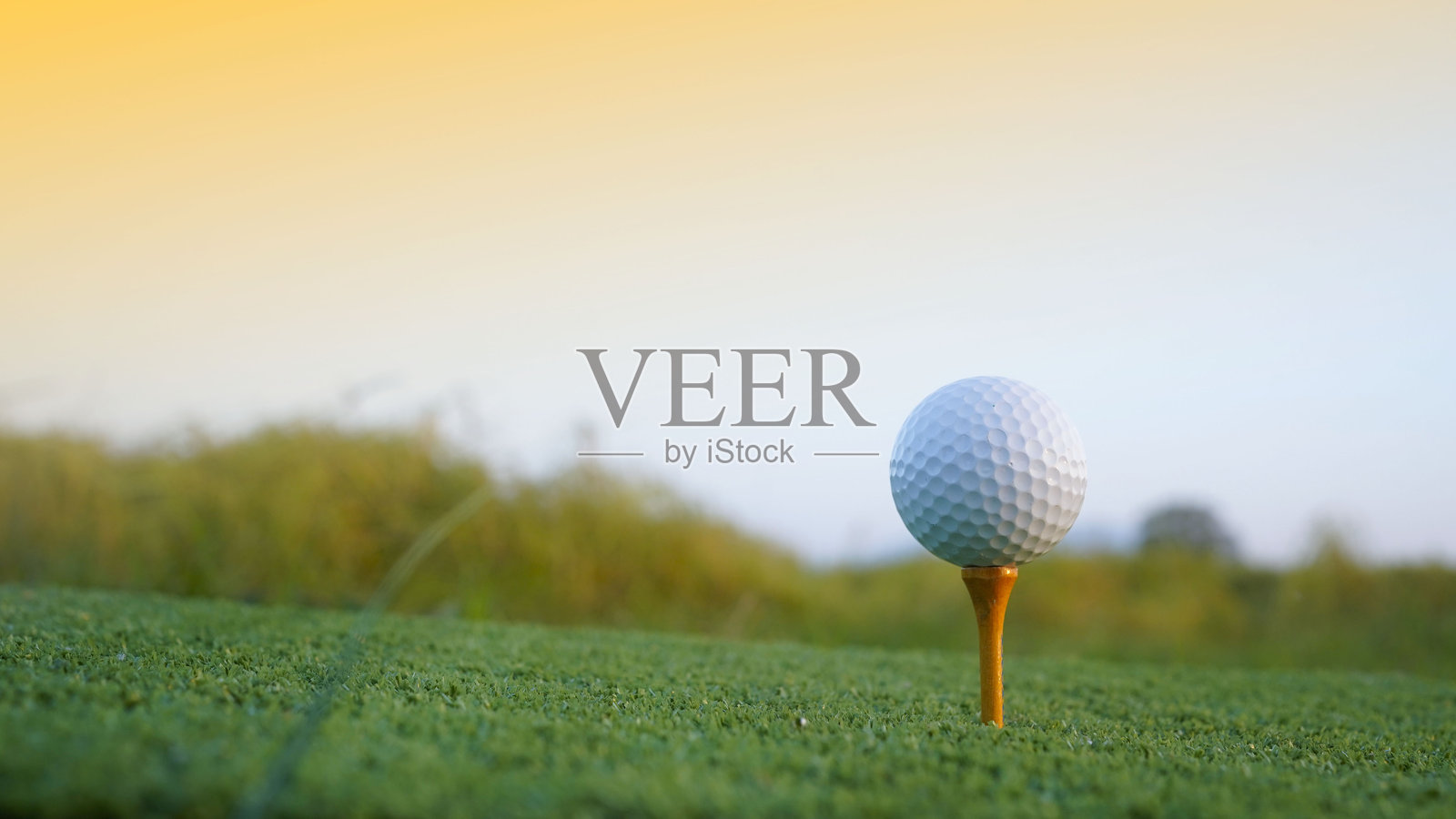 高尔夫球在美丽的高尔夫球场的球座上,夕阳西下。照片摄影图片