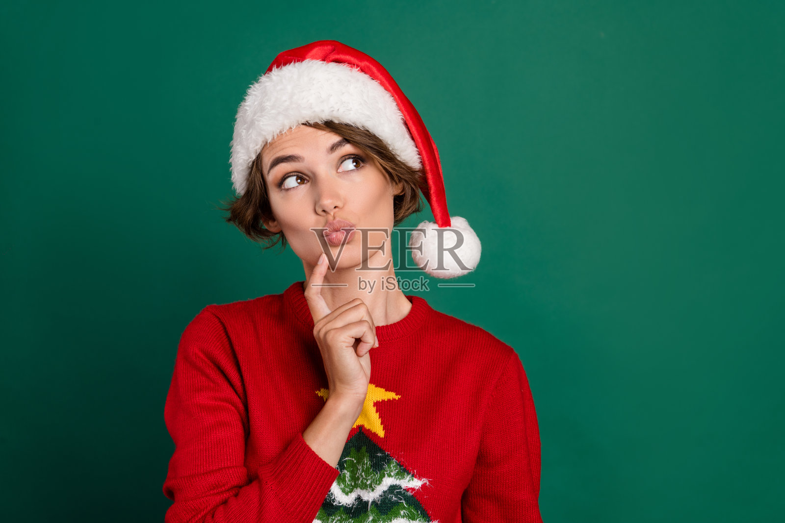 吸引人的人,撅嘴,手指触碰下巴,目光空洞,背景为绿色。照片摄影图片