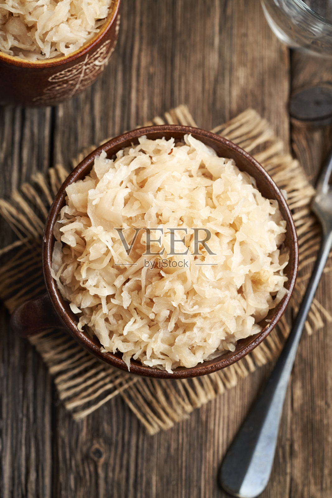Homemade fermented cabbage or sauerkraut in a pot on a table, top view照片摄影图片