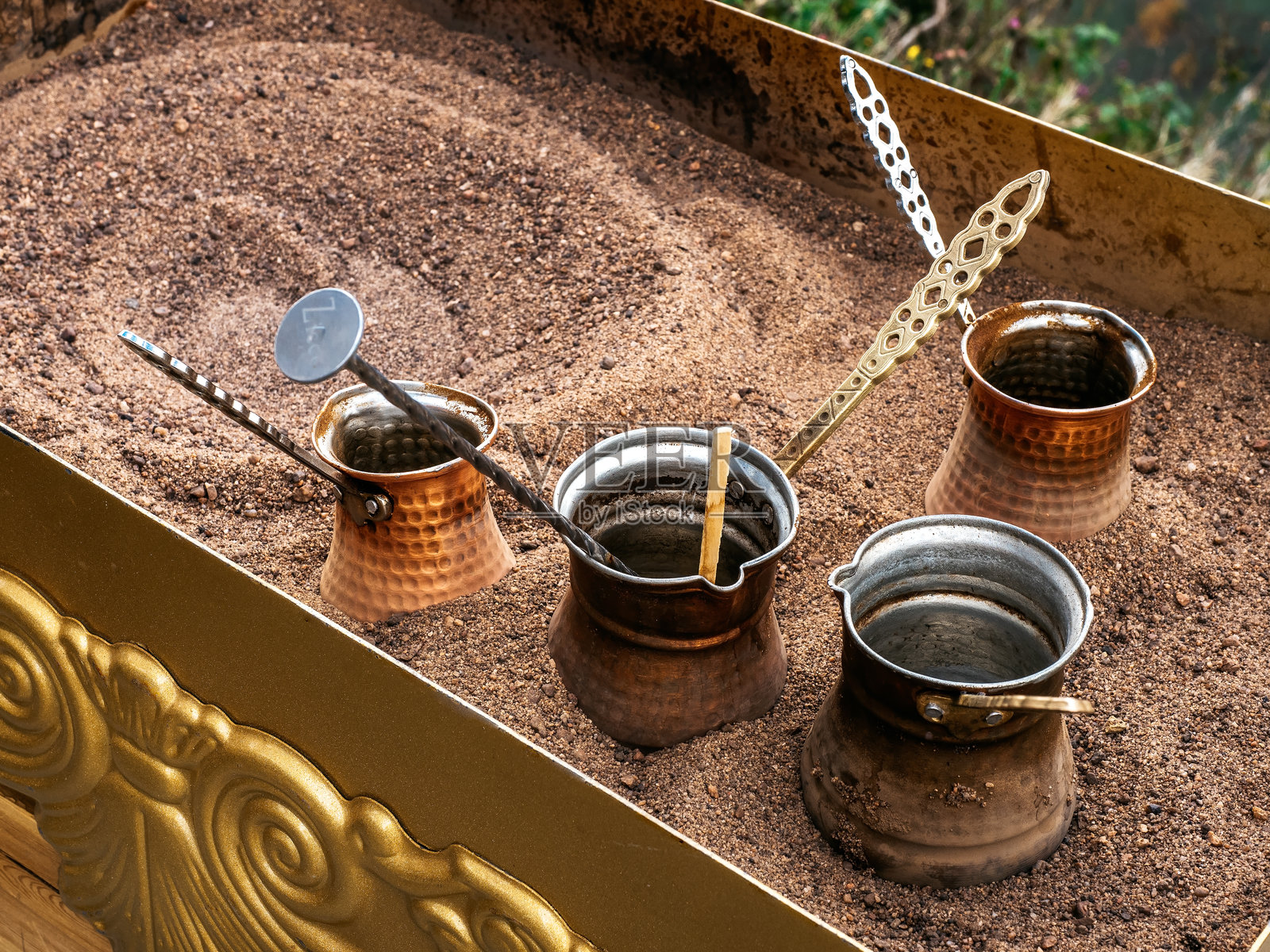 在沙子上制作咖啡。土耳其风格的咖啡准备,使用长柄铜壶在格鲁吉亚冲泡咖啡。照片摄影图片