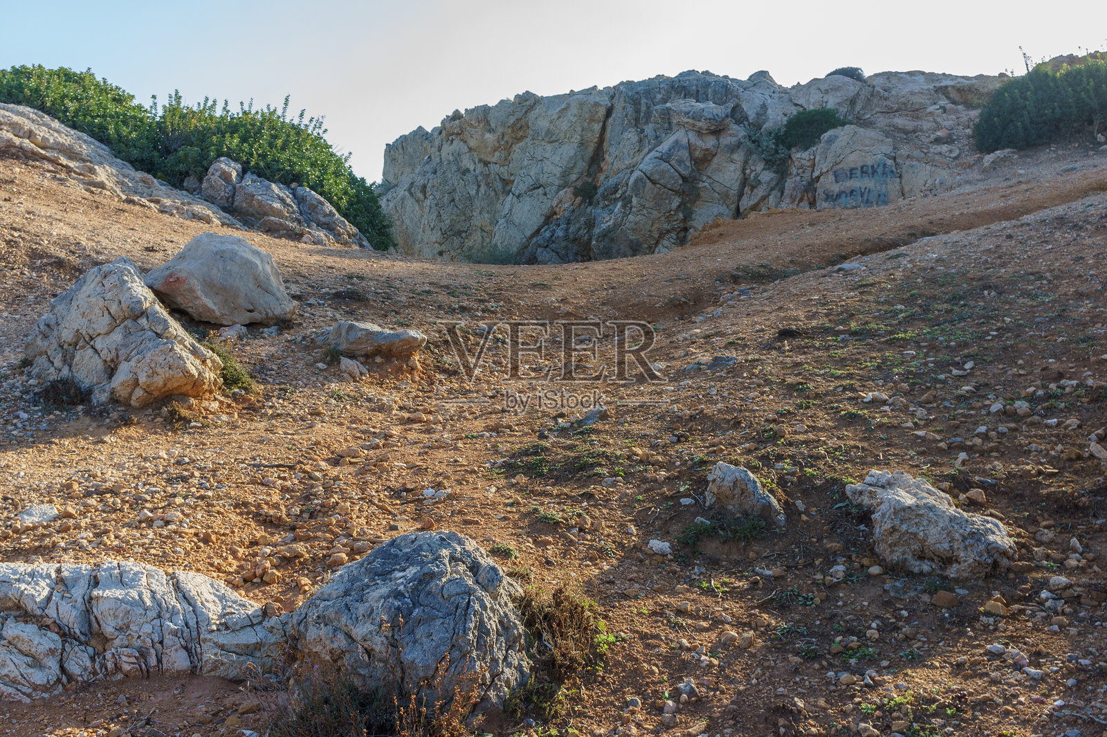 阳光照耀的小径蜿蜒穿过崎岖的地形,在宁静的早晨映衬着岩石山坡。照片摄影图片