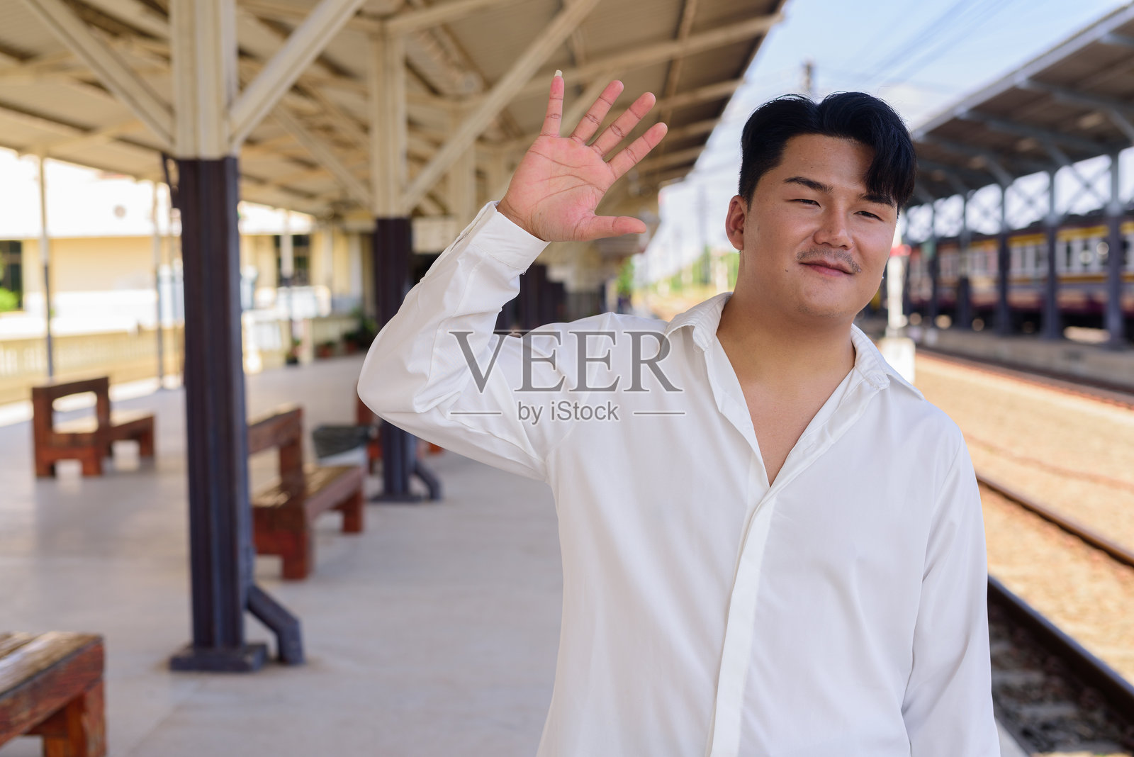 户外等候火车的帅气年轻亚洲男子肖像照片摄影图片