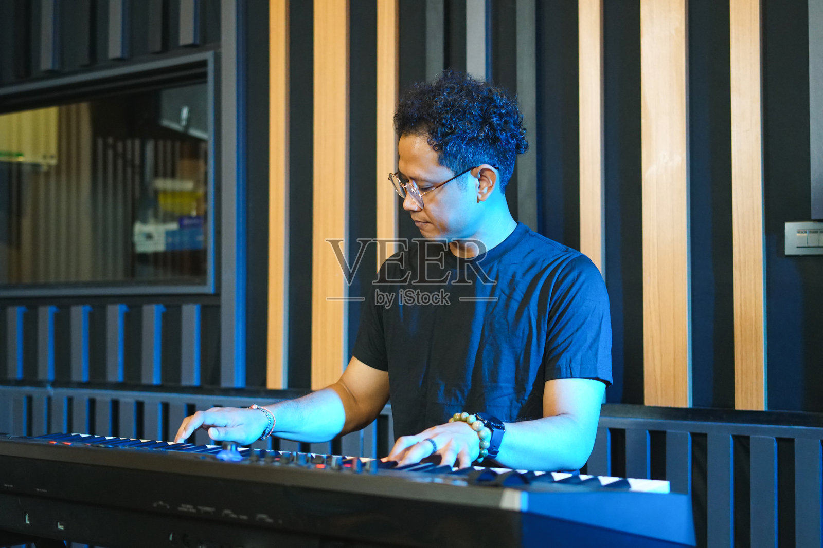 音乐家在家工作室里弹奏音乐键盘,亚洲男子在练习钢琴。照片摄影图片