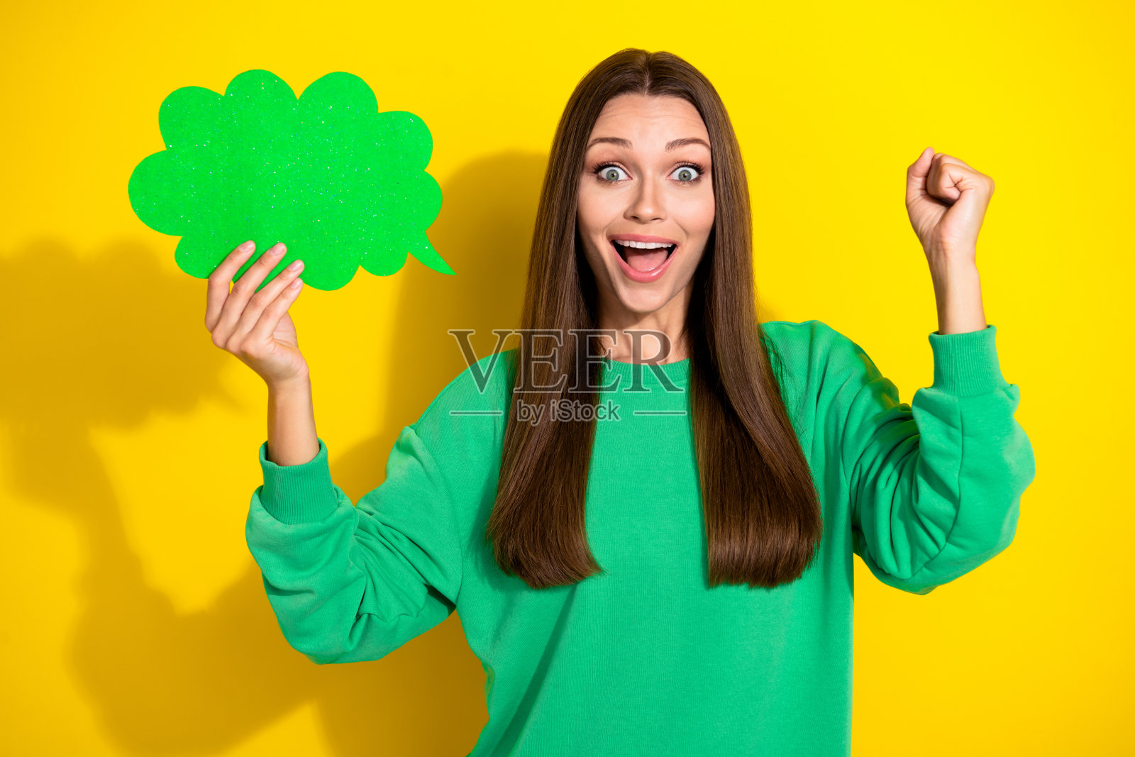 愉快的女士举起拳头庆祝成功,手持空白云卡,背景为黄色。照片摄影图片