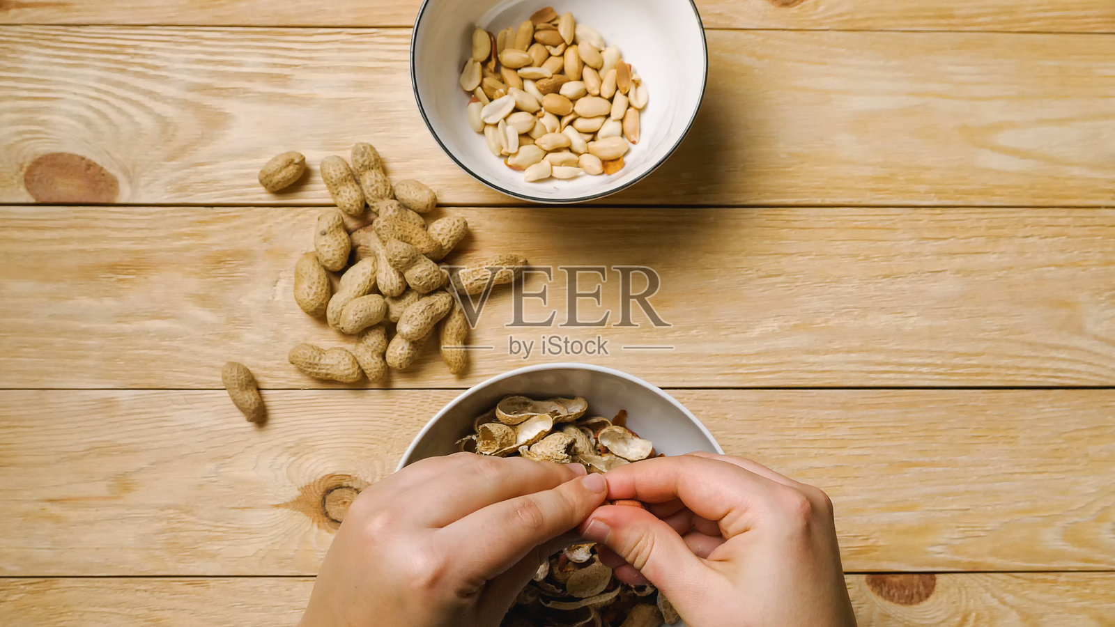 女性的手在碗上剥花生的特写镜头照片摄影图片