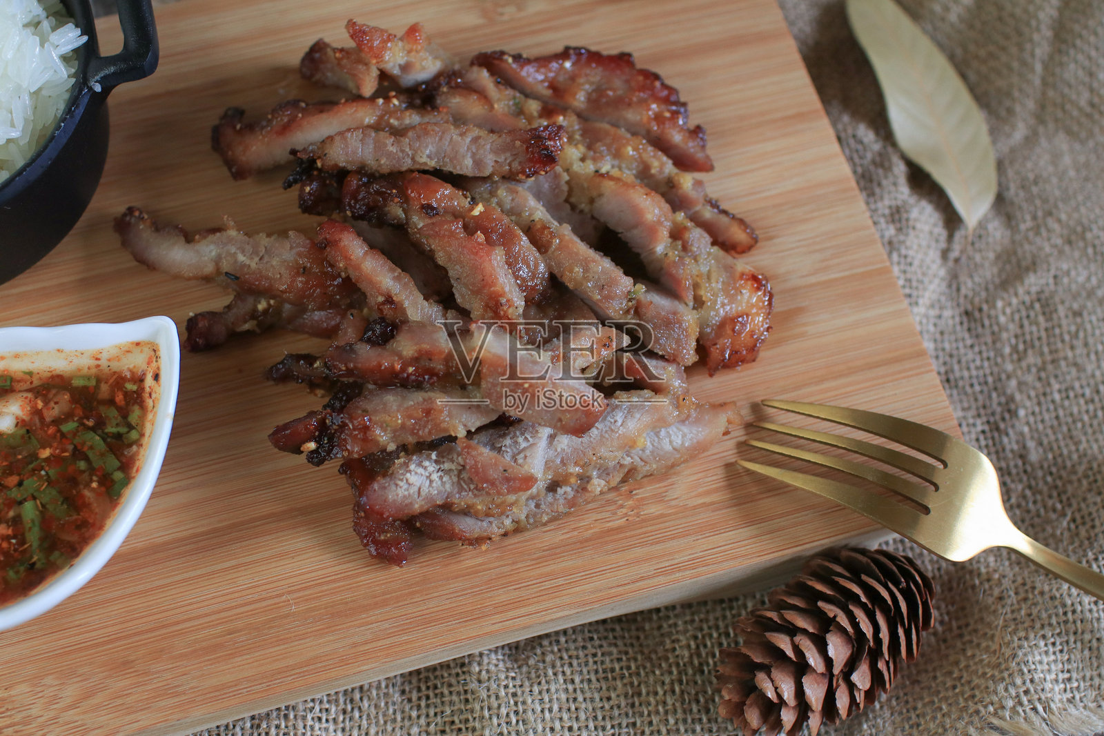 木砧板上的烤猪肉配辣酱和糯米。泰国当地街头美食。照片摄影图片