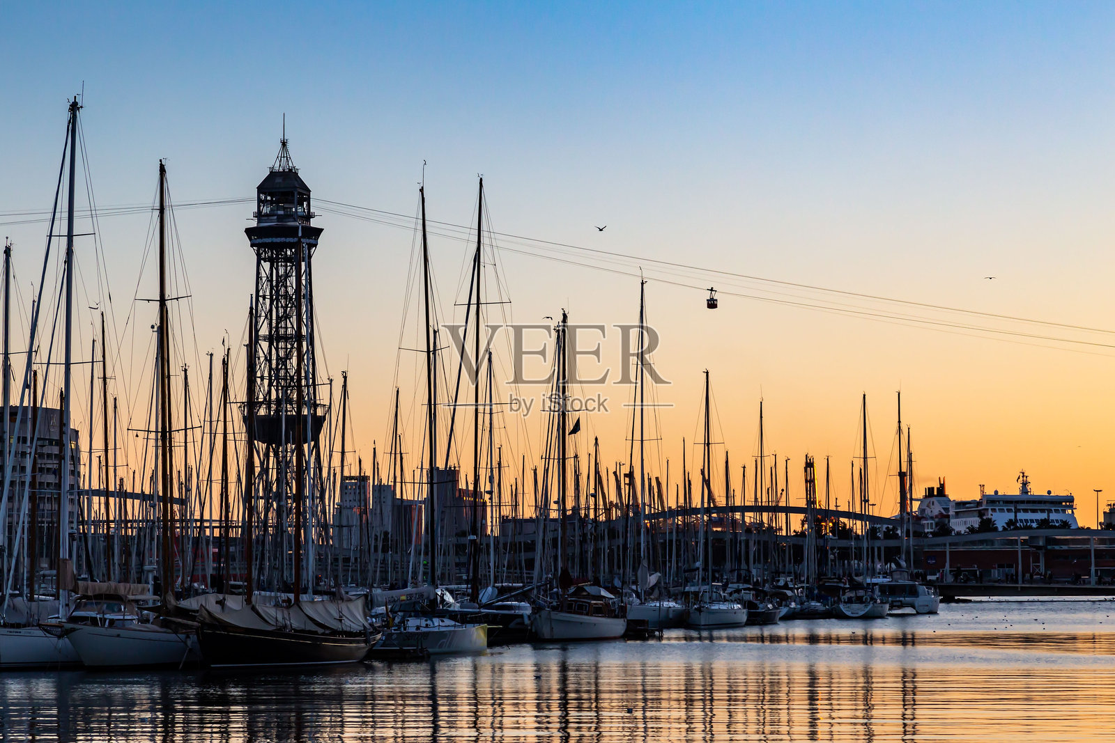 黎明时分宁静的港口景象,帆船在升起的太阳前形成剪影。照片摄影图片