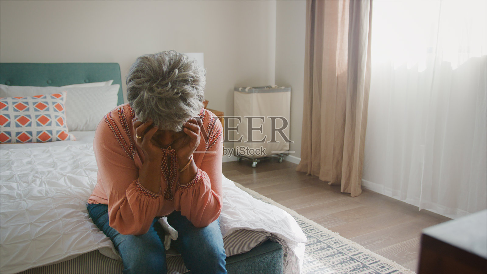 不快乐的老年女性双手托腮,因抑郁而坐在家中的卧室里。照片摄影图片