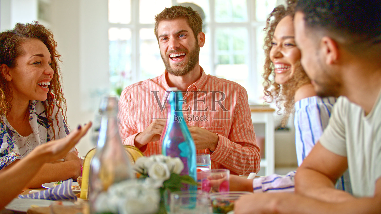 一群年轻朋友围坐在家中的桌子旁,共同享受美好的一餐。照片摄影图片