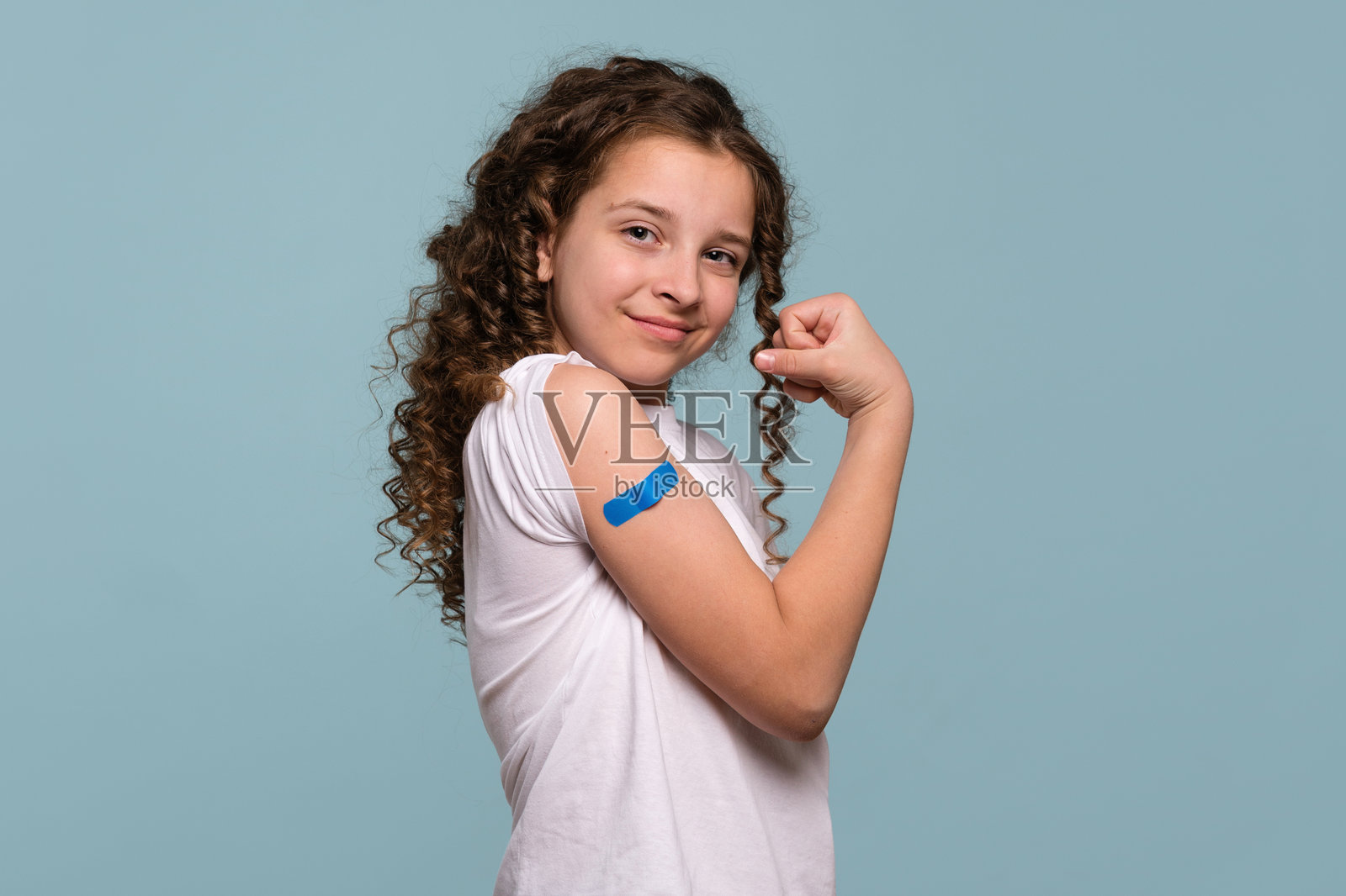 女孩在接种疫苗后,手臂上缠着蓝色绷带,展示肌肉。照片摄影图片