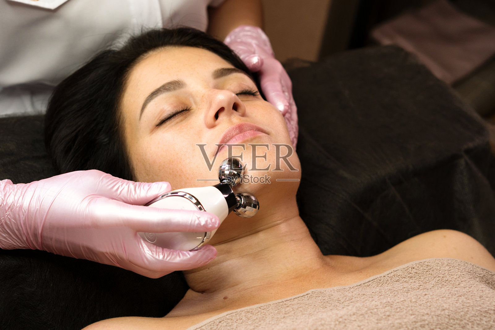 女性在水疗中心接受放松的微电流面部按摩。照片摄影图片