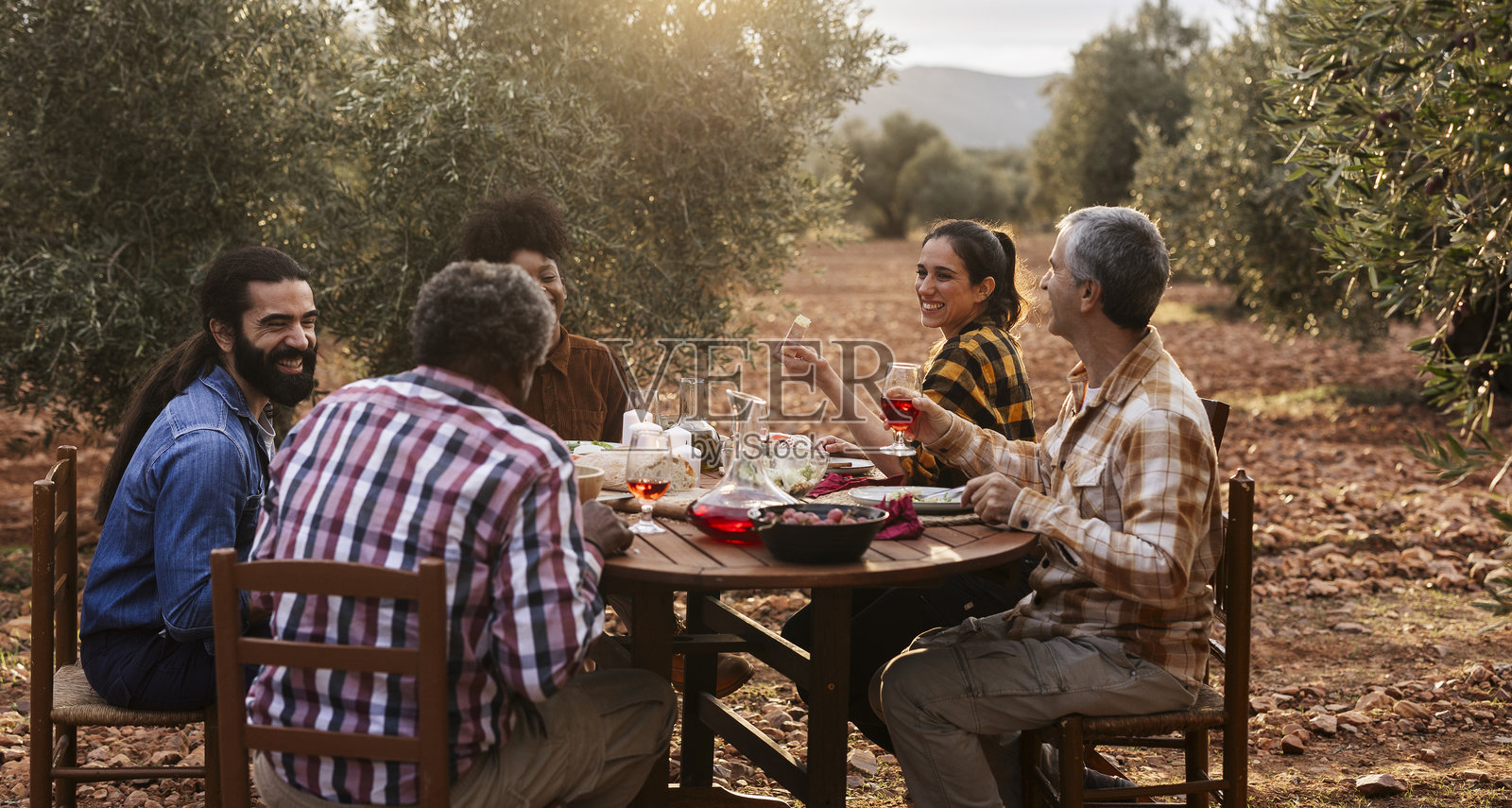 农民们在橄榄树林中享受日落时的聚餐照片摄影图片