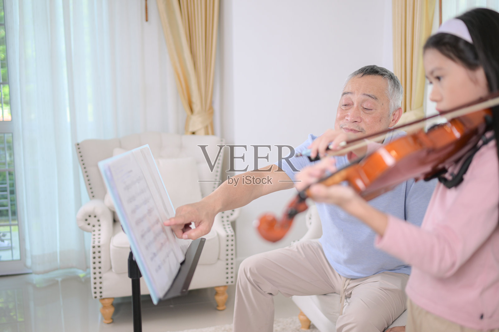 一个女孩小提琴手和她的祖父在家一起练习音乐照片摄影图片