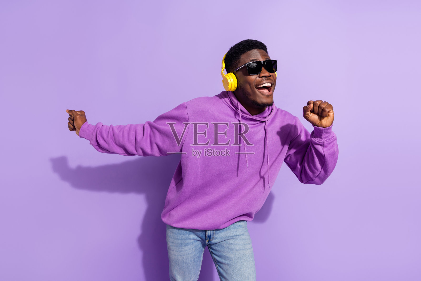 满意的帅气人士在紫色背景下享受放松时光,听着MP3音乐。照片摄影图片