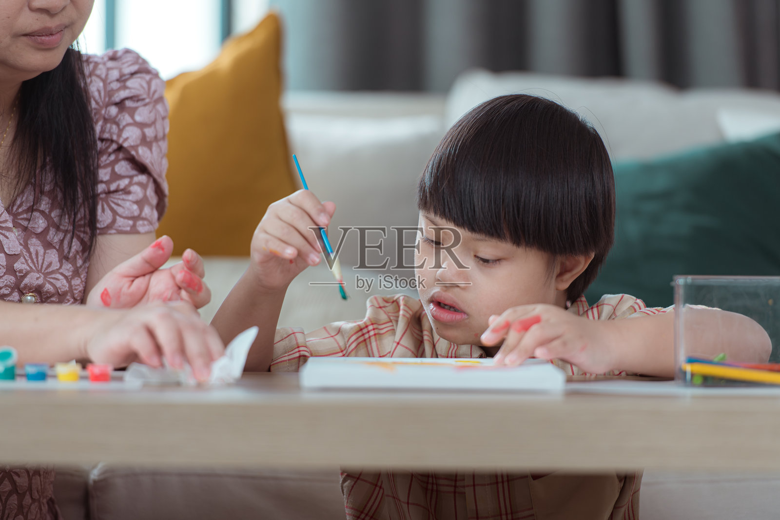 一个特殊的孩子和他的妈妈在家里的客厅一起画画和涂色照片摄影图片