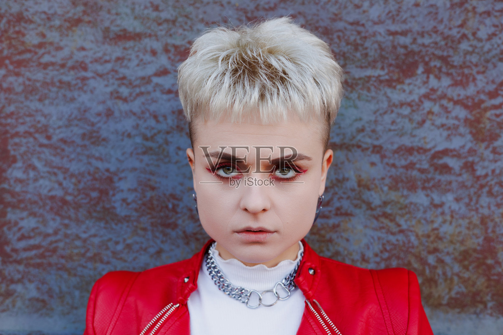 自信的金发女性,妆容鲜艳,正对着镜头,背景为纹理蓝色。照片摄影图片