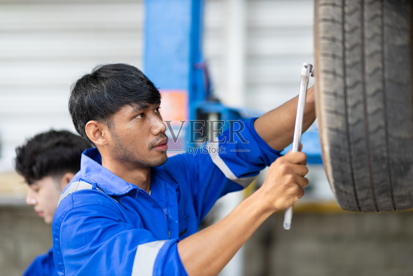 汽车修理工在服务站工作。专业技师正在检查一辆升起的汽车。汽车修理工正在修理汽车悬挂,更换零件并检查汽车轮胎。照片摄影图片
