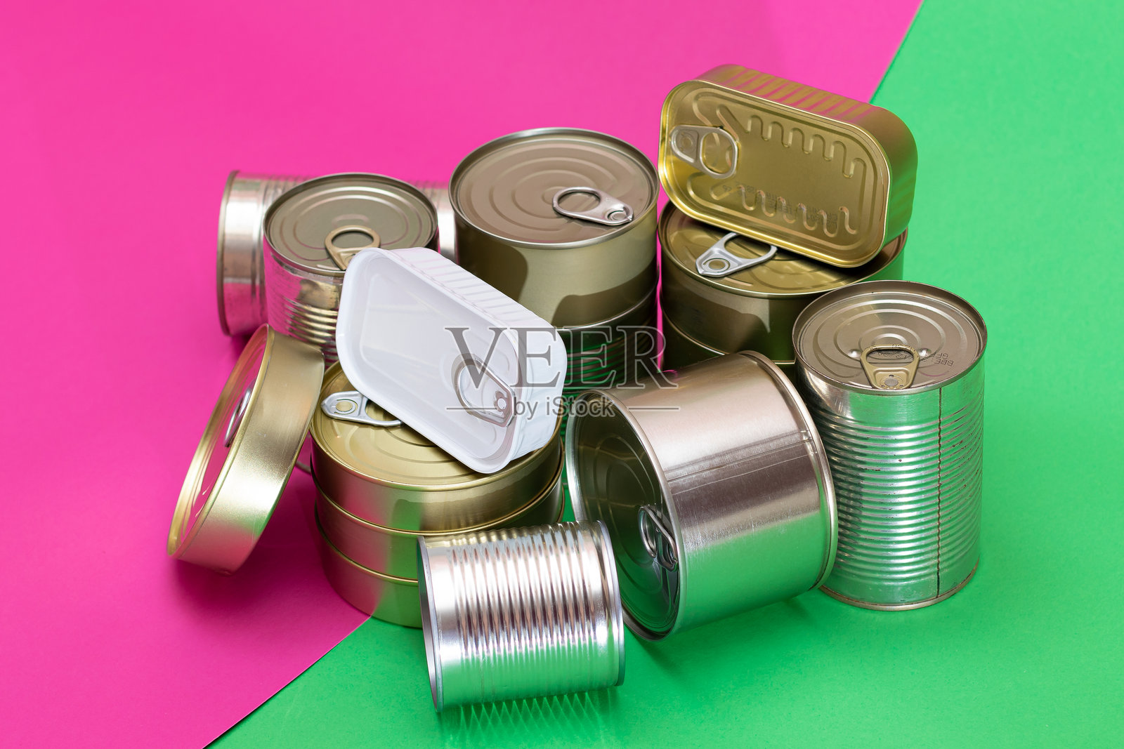 一组叠放的锡罐置于分割的绿色和青色背景上照片摄影图片