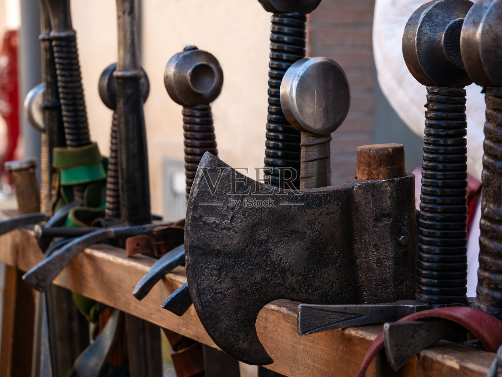 特写镜头展示一个木制架子,上面摆放着中世纪的战斗武器,如斧头和剑。照片摄影图片