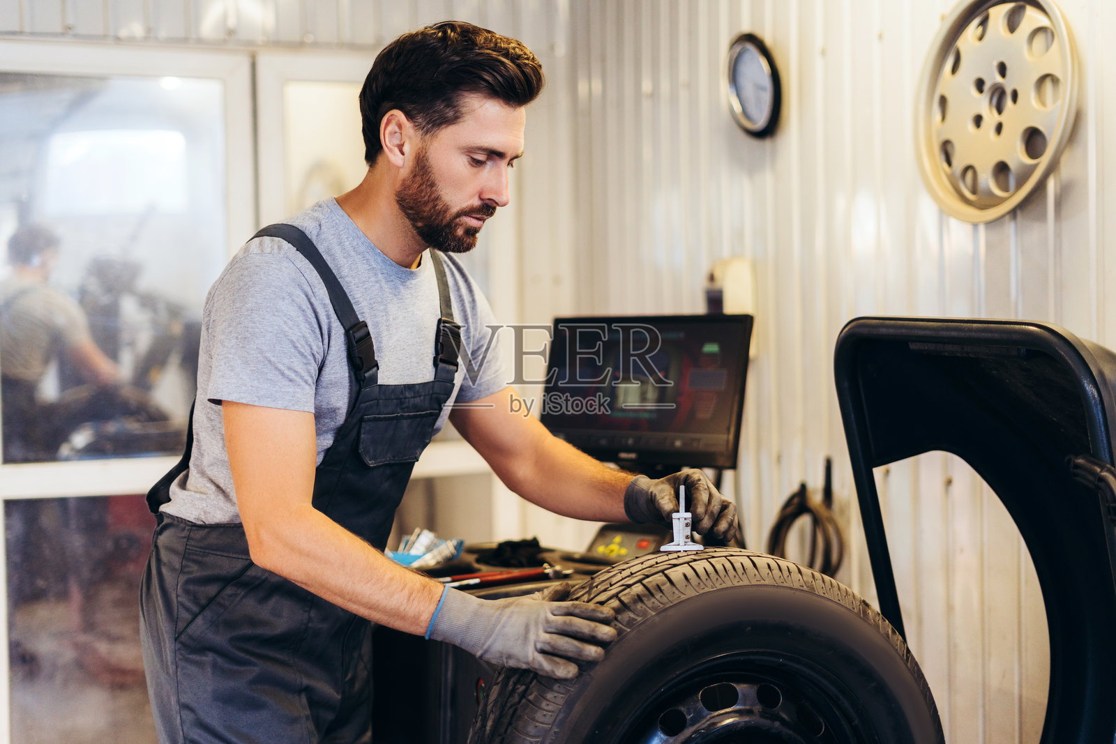 严肃而沉思的修理工,在现代服务站修理轮胎。广告概念照片摄影图片
