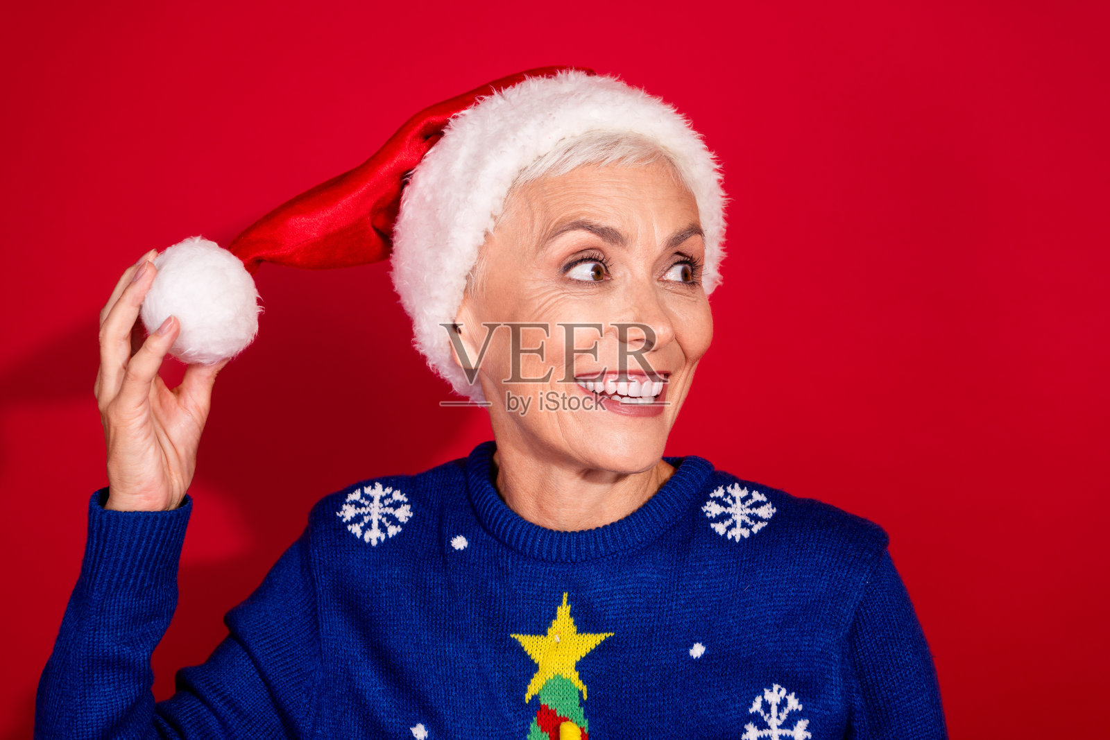 可爱的积极退休女性穿着时尚毛衣,在红色背景下庆祝新年照片摄影图片