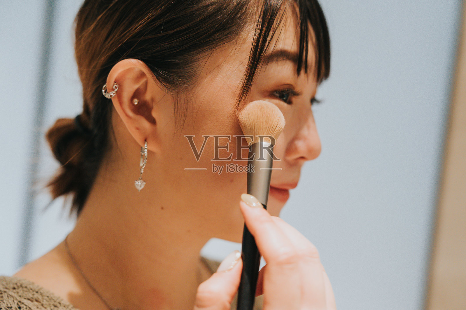 快乐的Z世代女孩们在中国大湾区的珠海旅行。一位亚洲女孩正在酒店房间的卫生间里化妆。照片摄影图片