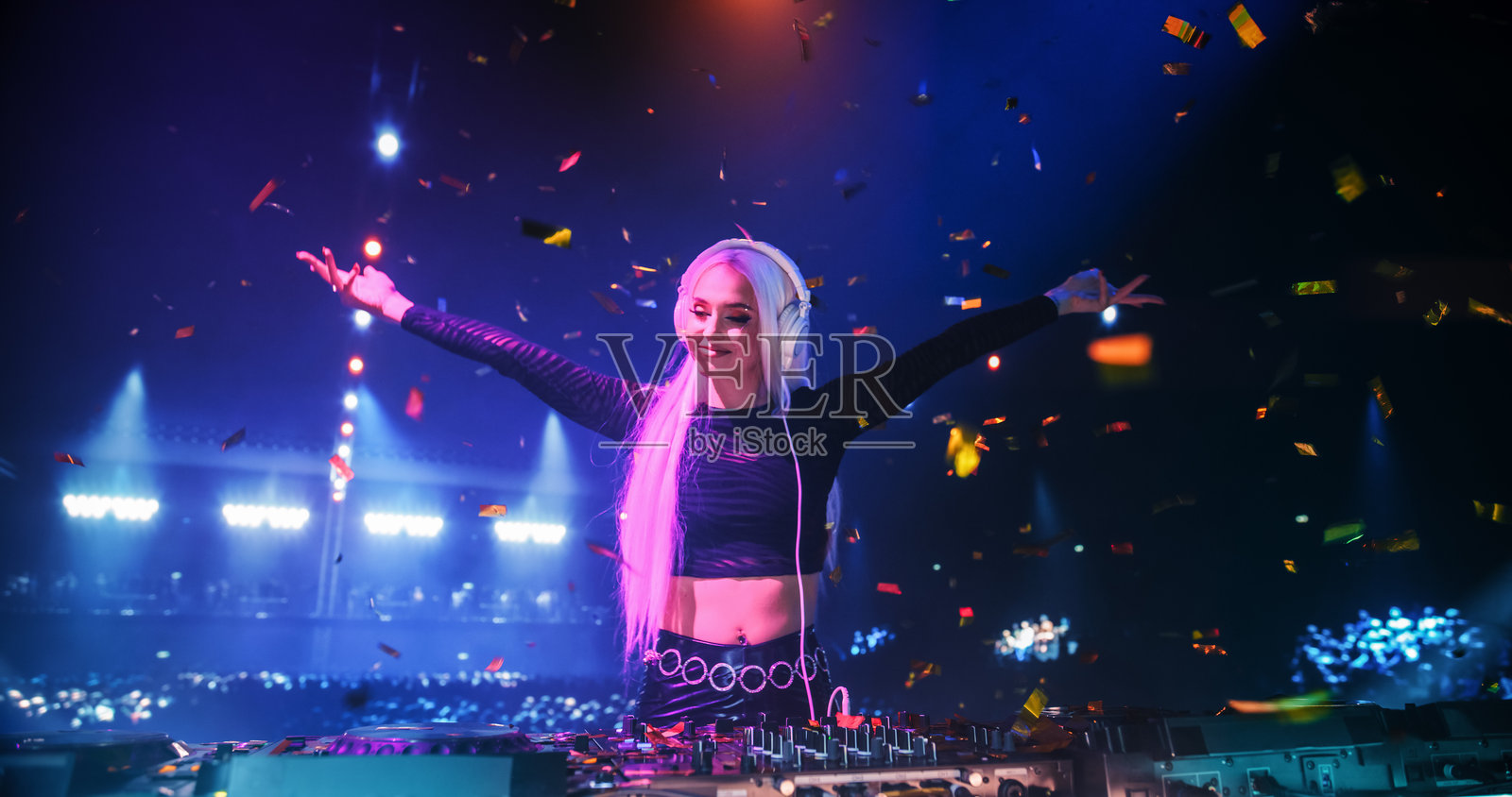 年轻美丽的女性DJ在夜总会播放舞曲、电子舞曲、科技音乐和浩室音乐,吸引了热情的音乐粉丝。霓虹灯和兴奋的人群营造出节日的派对氛围。照片摄影图片