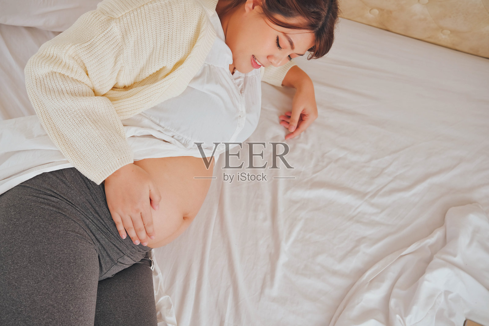 一位孕妇安静地躺在床上,享受母亲身份的美好与宁静。照片摄影图片