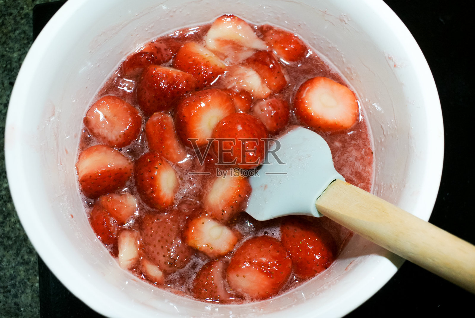 高角度视图的草莓与糖浆在桌子上的碗里照片摄影图片