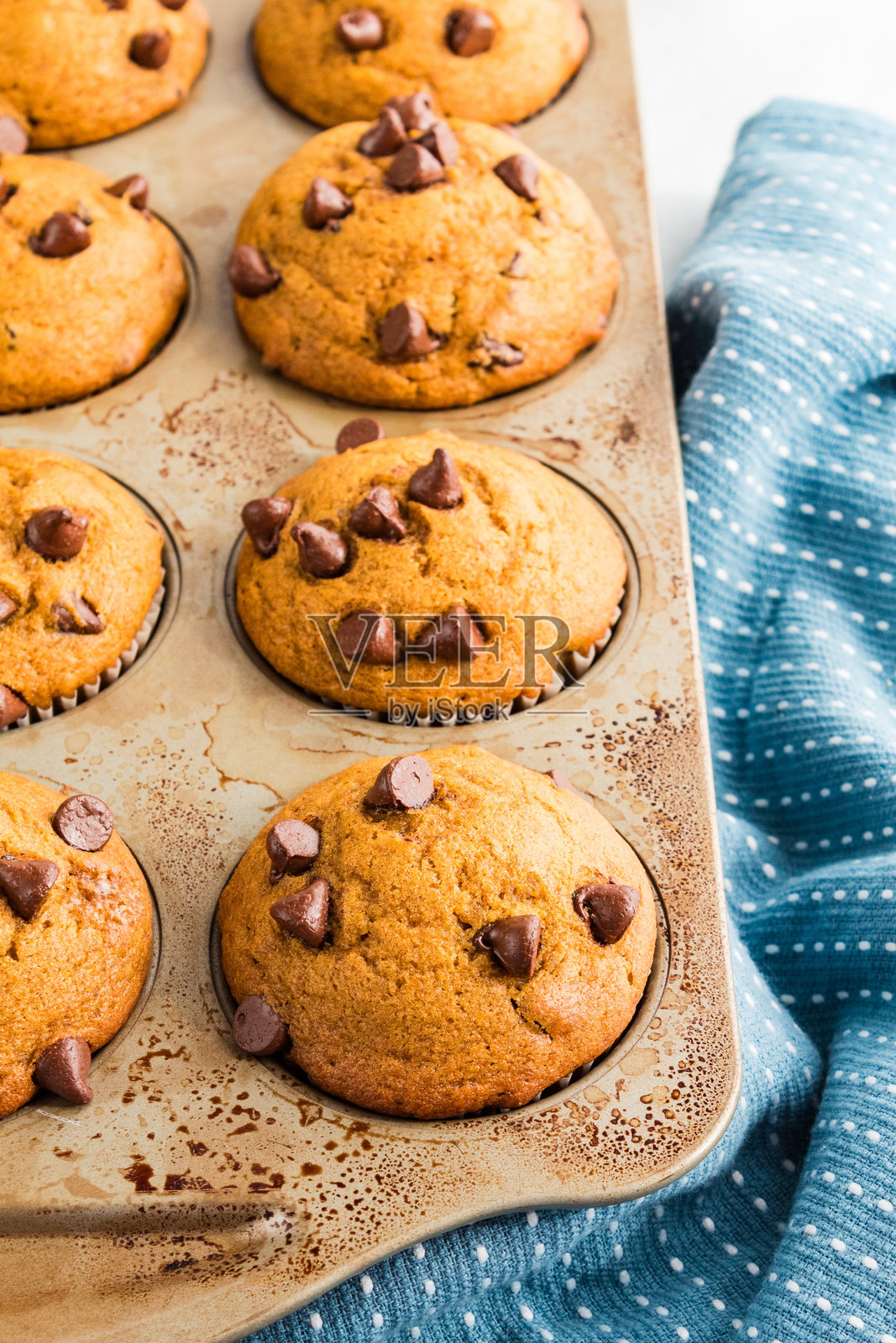 南瓜巧克力碎片松饼放在烤盘里,旁边有一块温馨的蓝色布料照片摄影图片