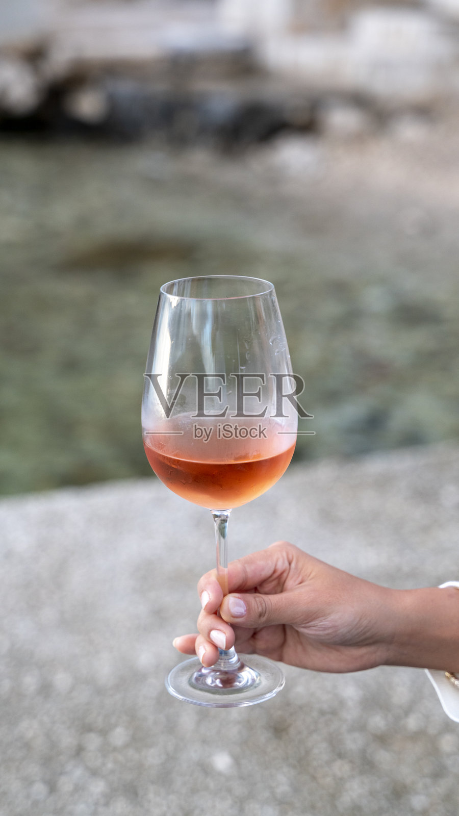 女人在海边举着一杯玫瑰红酒照片摄影图片