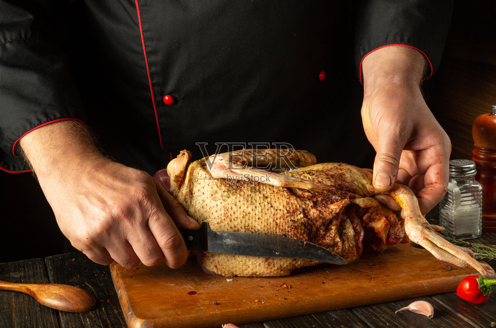 一位厨师熟练地在木板上切割一只美味的烤鸭,展现出丰富的风味。新鲜的香草和香料为这道令人垂涎的菜肴增添了风味,准备好上菜。照片摄影图片