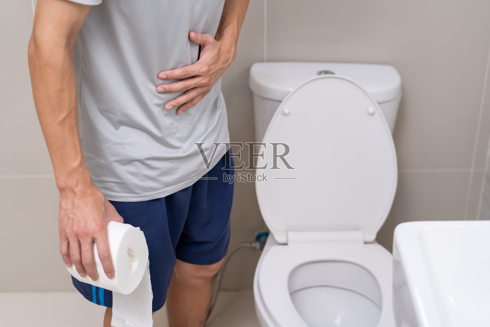 厕所里的便秘和腹泻。痛苦的男人捂着肚子,腹痛难忍。结肠炎问题,食物中毒,腹部疼痛,腹部,厕所里的便秘,肚子疼,卫生。照片摄影图片